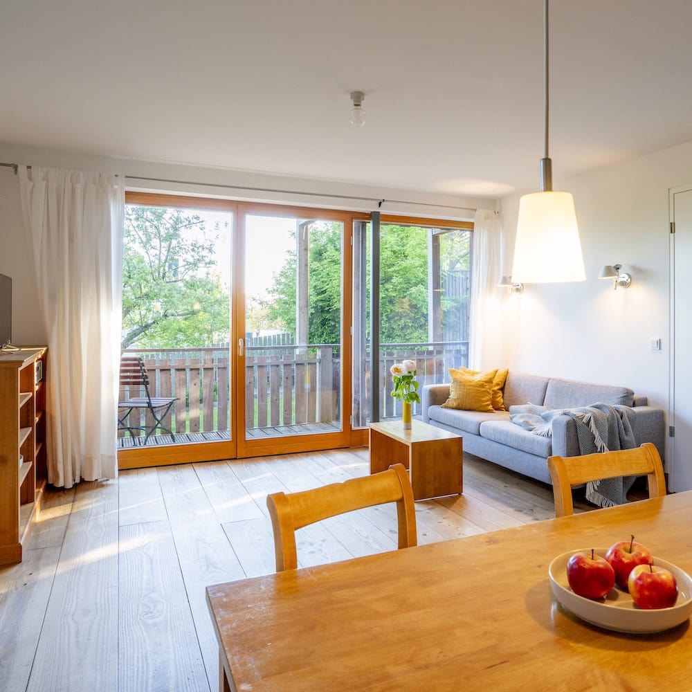 Wohnzimmer mit Sofa, Massivholzmöbeln, Holzdielen und Blick in den Garten, Ferienwohnung 4, Apfelgarten Usedom Reetzow