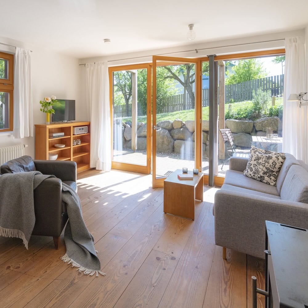 Wohnraum mit Ledersessel, Sofa, Massivholzmöbeln, Holzdielen und Blick in den Garten, Ferienwohnung 2, Apfelgarten Usedom Reetzow, barrierefrei